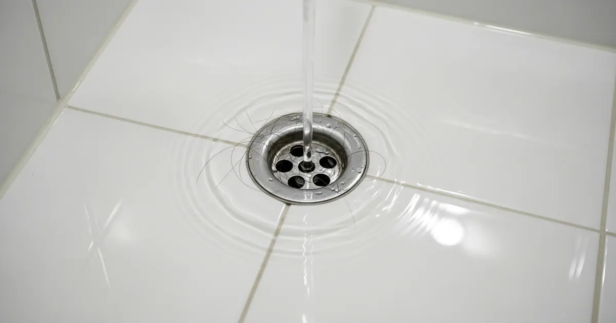 Slow-draining shower with water pooling around the drain